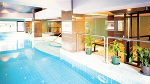 Ein hallenbad mit gefliesten Wänden und einer Glasbrüstung.