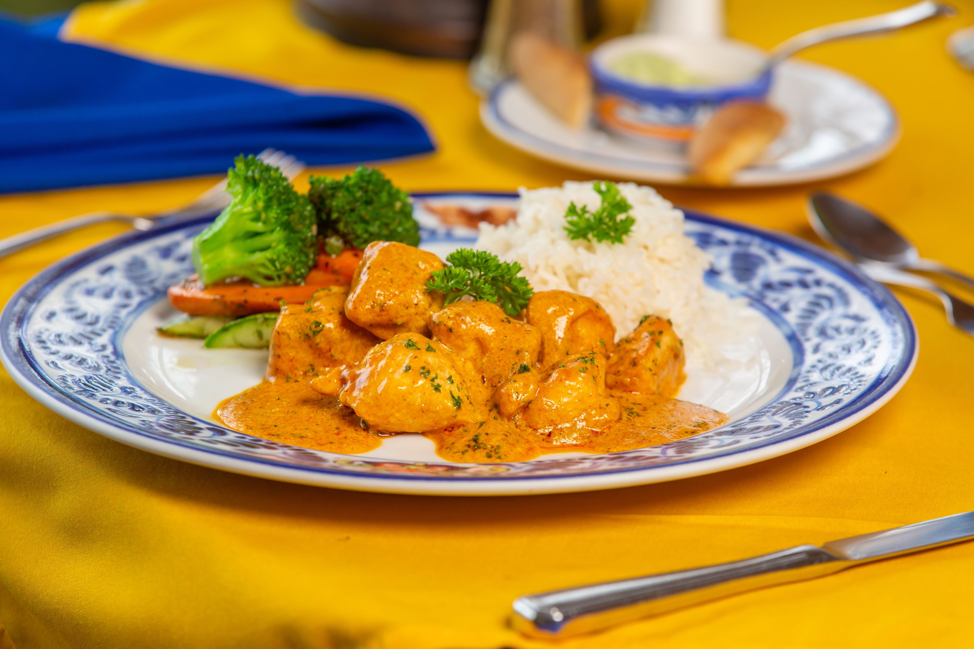 A plate of chicken curry with rice and vegetables.
