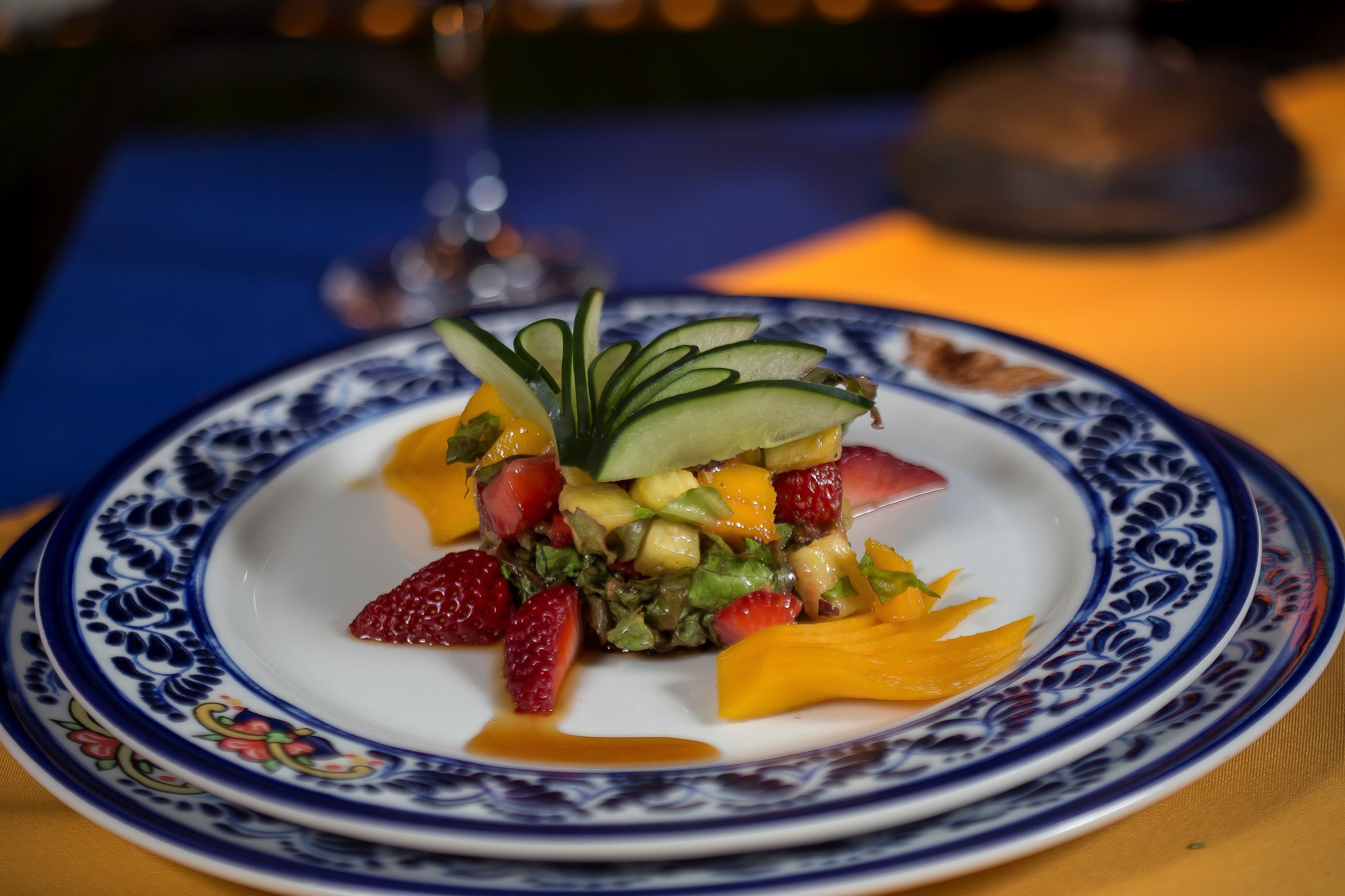 A plate of fruit salad with a decorative blue and white pattern on the rim.