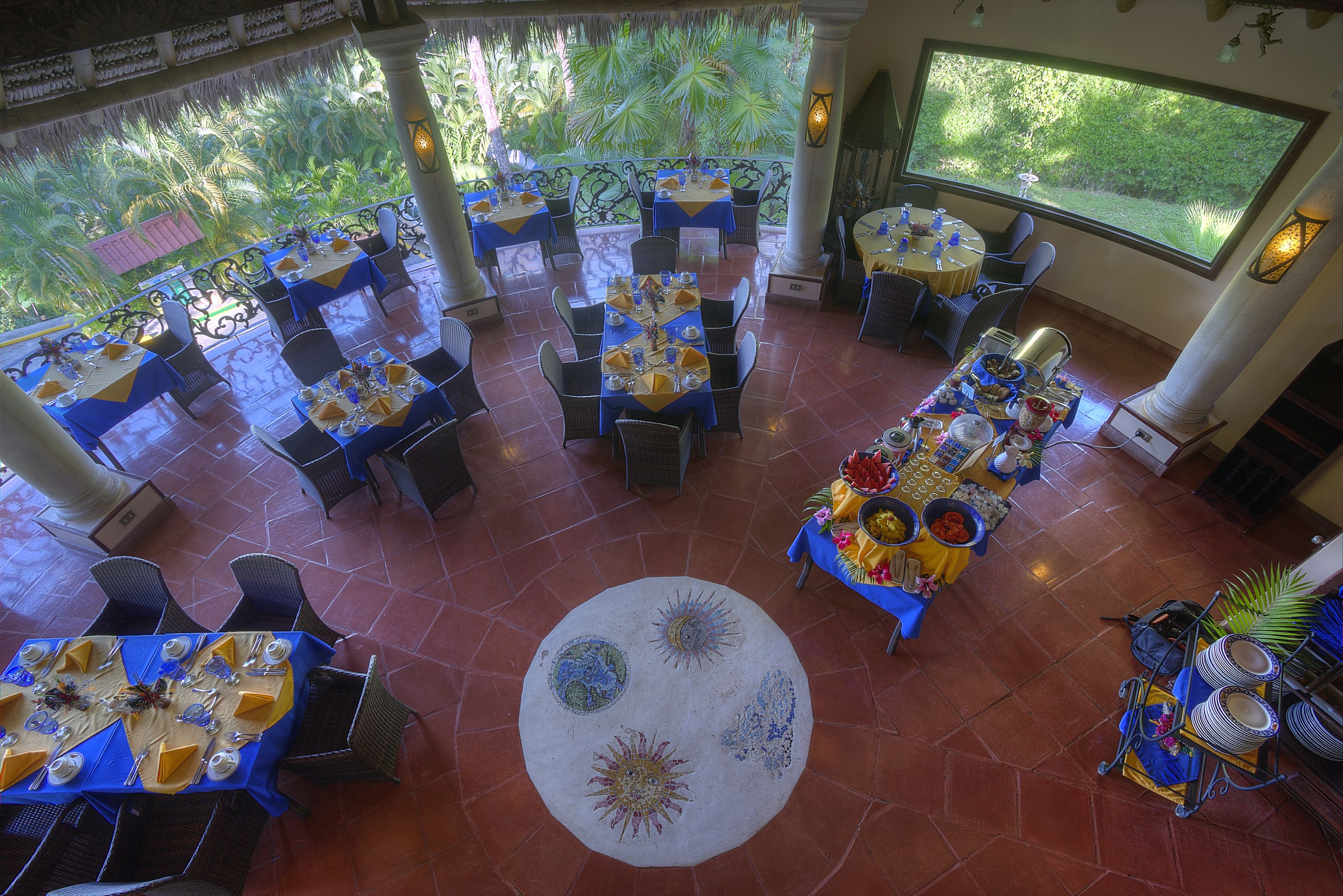 A restaurant with multiple tables, chairs, and a central decorative rug.