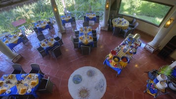 Un restaurante con varias mesas, sillas y un tapete decorativo en el centro.