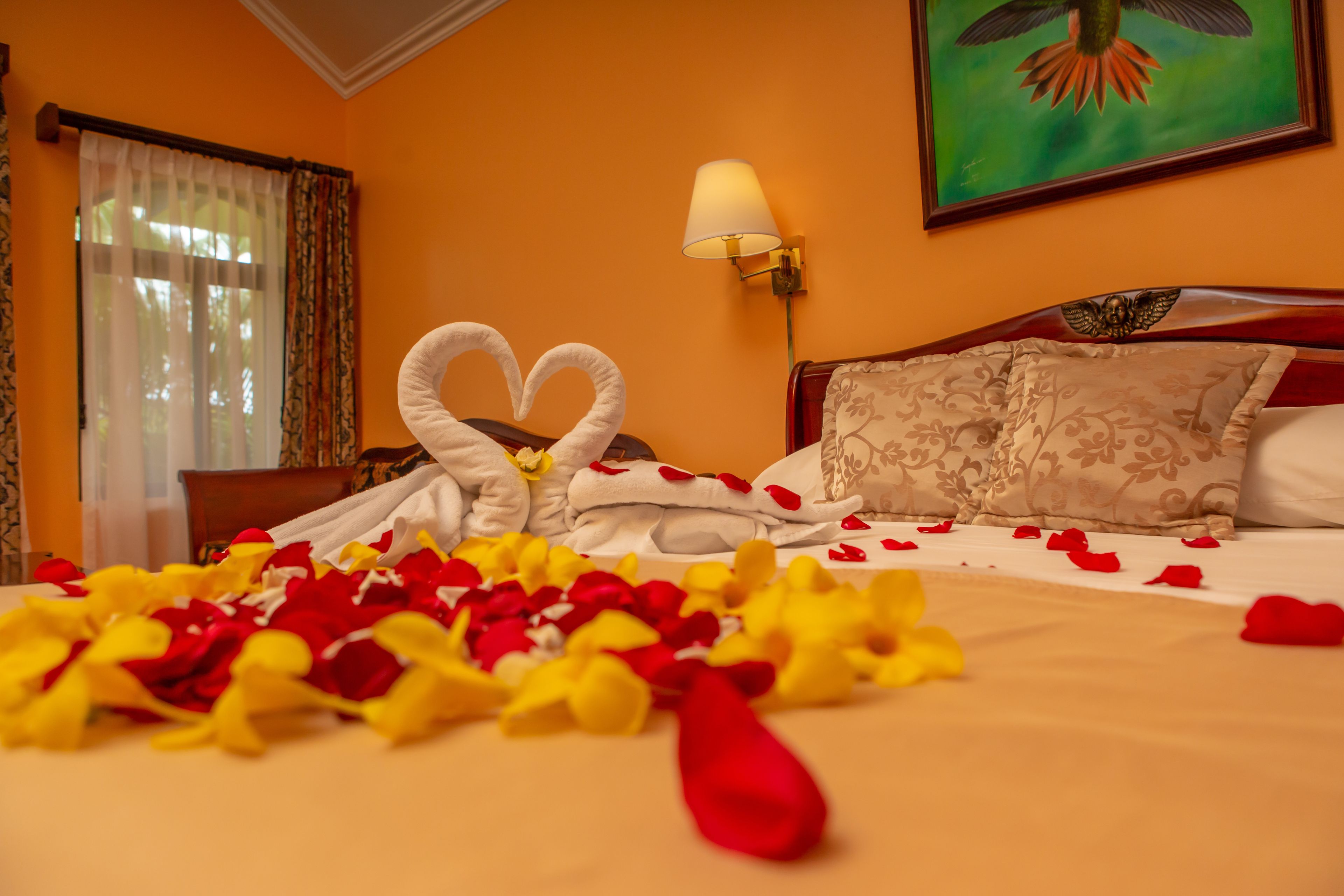 Une chambre d’hôtel avec un lit, une serviette pliée en forme de cœur et un tableau accroché au mur.