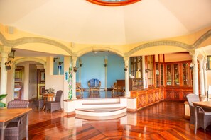 A spacious interior with a high ceiling, ornate columns, and a central staircase leading to an upper level. - Hotel Cuna Del Angel (Bahía Ballena)