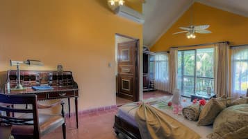 A room with a bed, a desk with a lamp, and a ceiling fan.