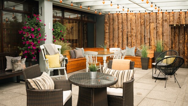 An outdoor patio with wicker furniture, a round table, and string lights. - Downhill Inn (Ballina)