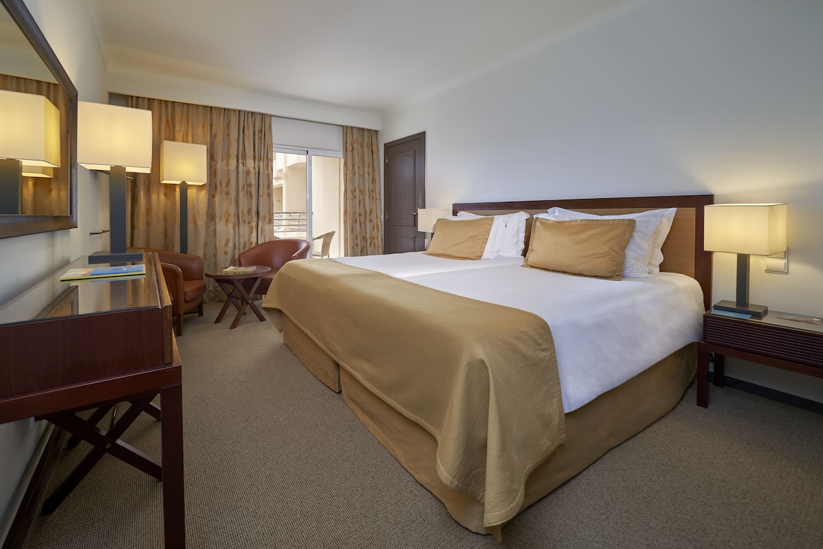 Een hotelkamer met een groot bed, een bureau, een stoel en een lamp.