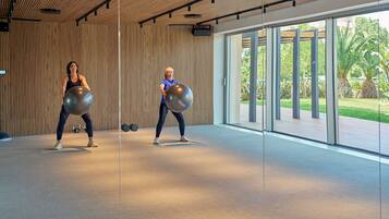 A modern gym with wooden panel walls and large windows offering a view of greenery outside.