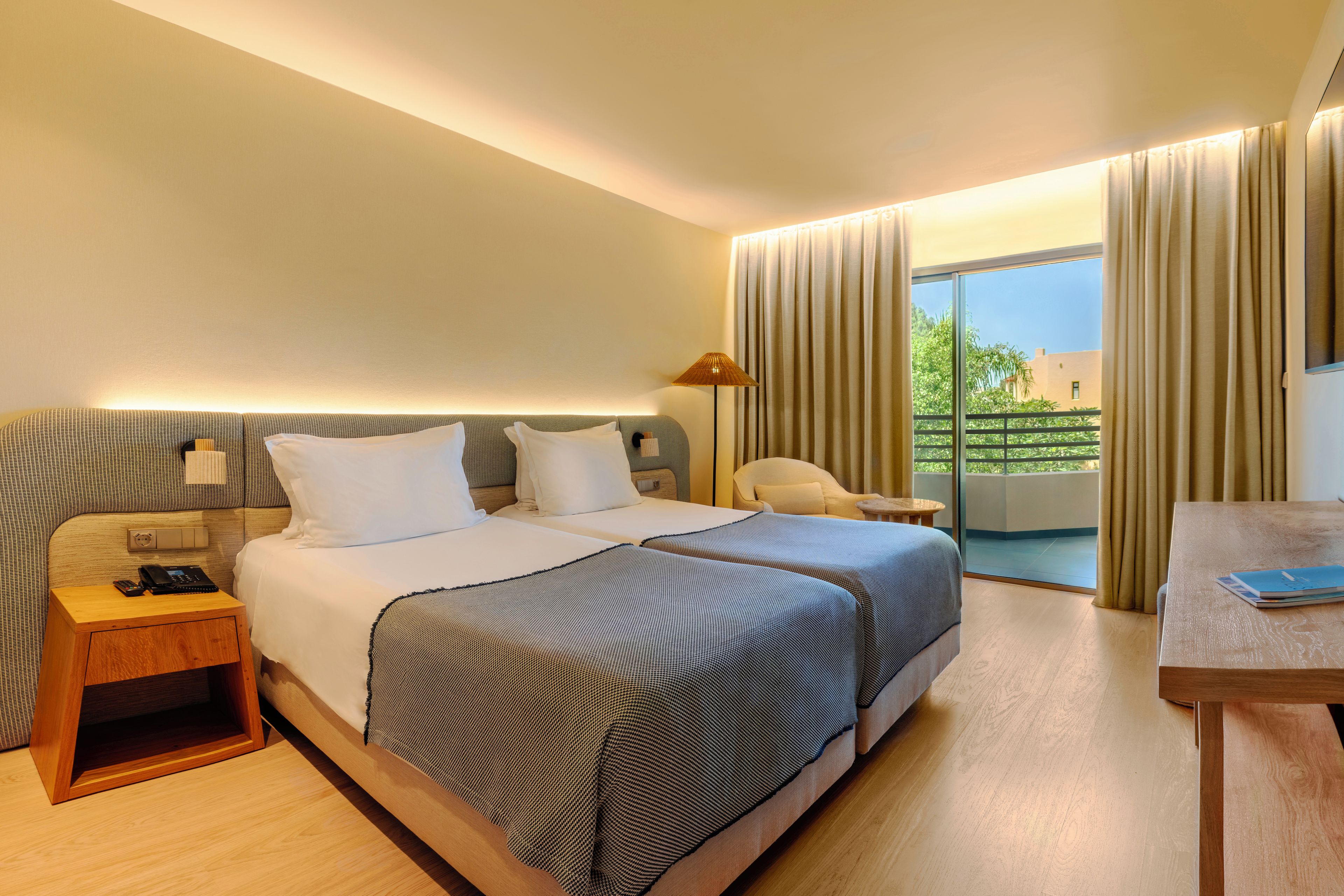 Une chambre d’hôtel avec un lit, des tables de chevet, un bureau et une vue sur l’extérieur.