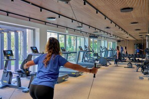 Une salle de sport équipée de tapis de course, de vélos d’exercice et d’appareils de musculation.