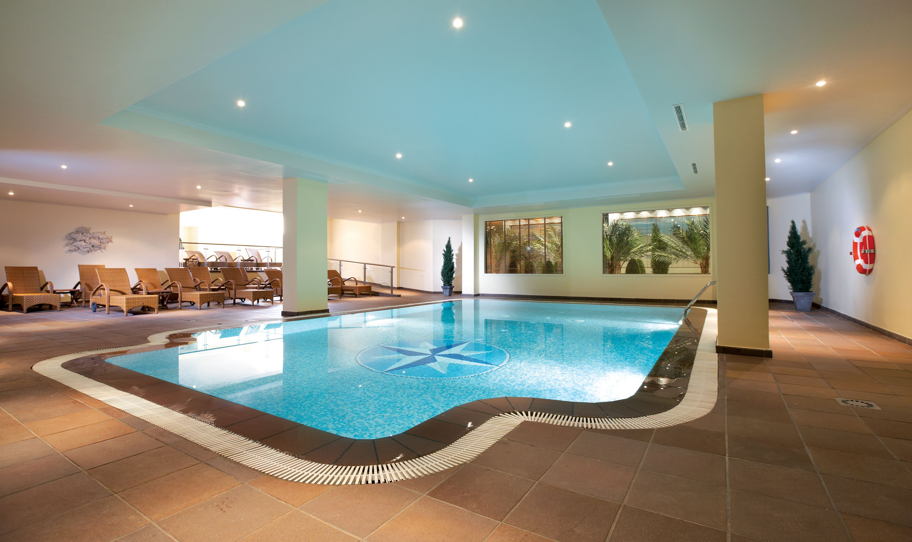Piscina con diseño de estrella, sillas de descanso y plantas en macetas.