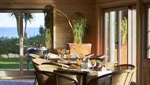 An outdoor dining area with wicker furniture, a table set with glasses, and a potted plant.