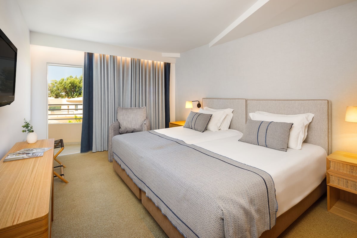 Een moderne hotelkamer met een groot bed, een bureau en uitzicht op de omgeving.