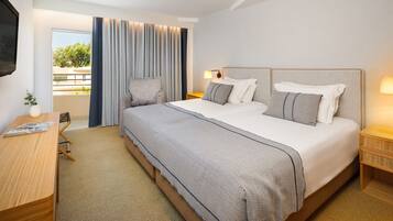 A modern hotel room with a large bed, a desk, and a view of the outdoors.