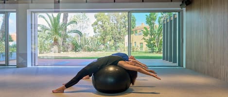 A spacious room with large windows, a ceiling with wooden slats, and a large exercise ball.