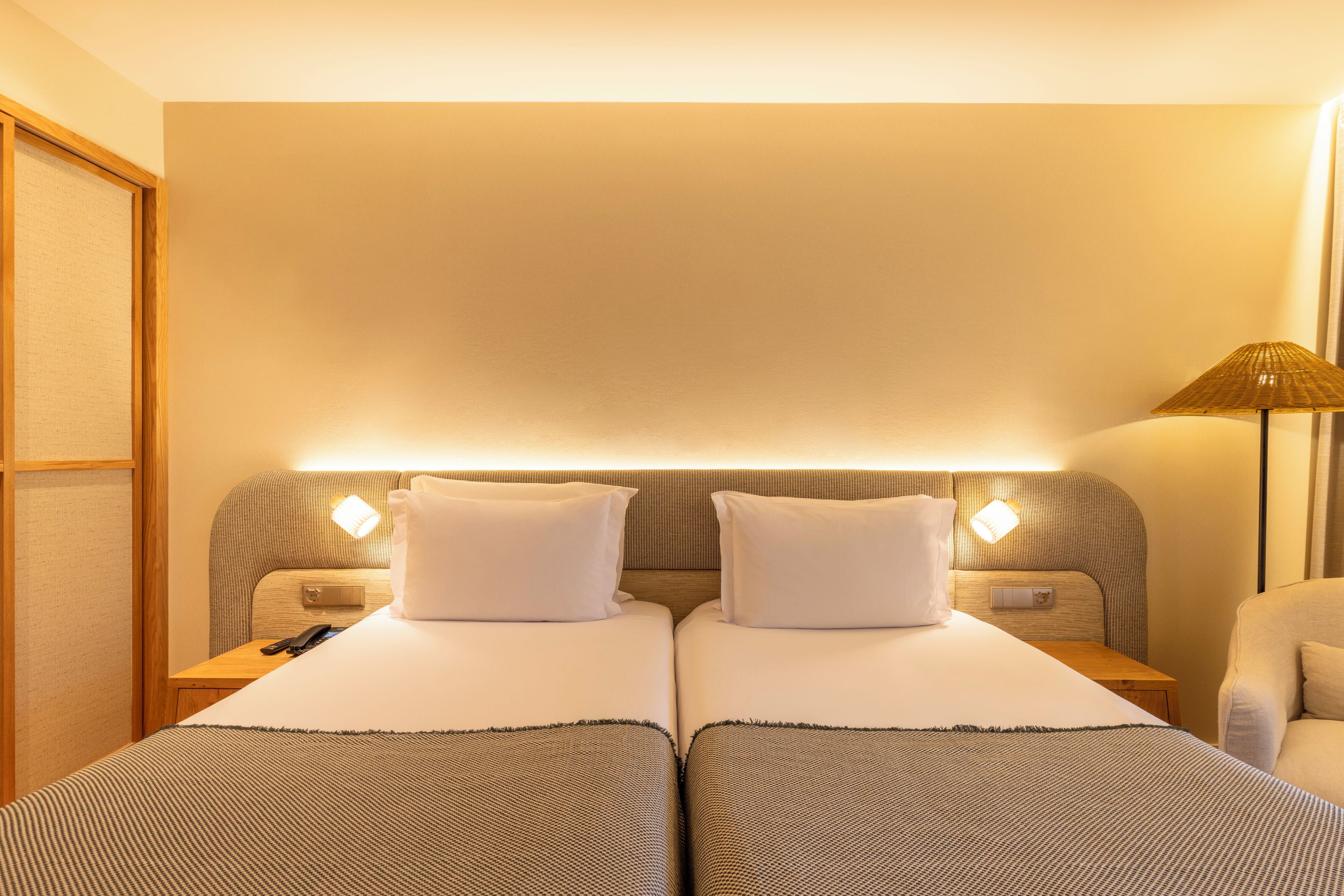 Habitación de hotel con cama doble, dos lámparas de noche, una mesita de noche y una silla.