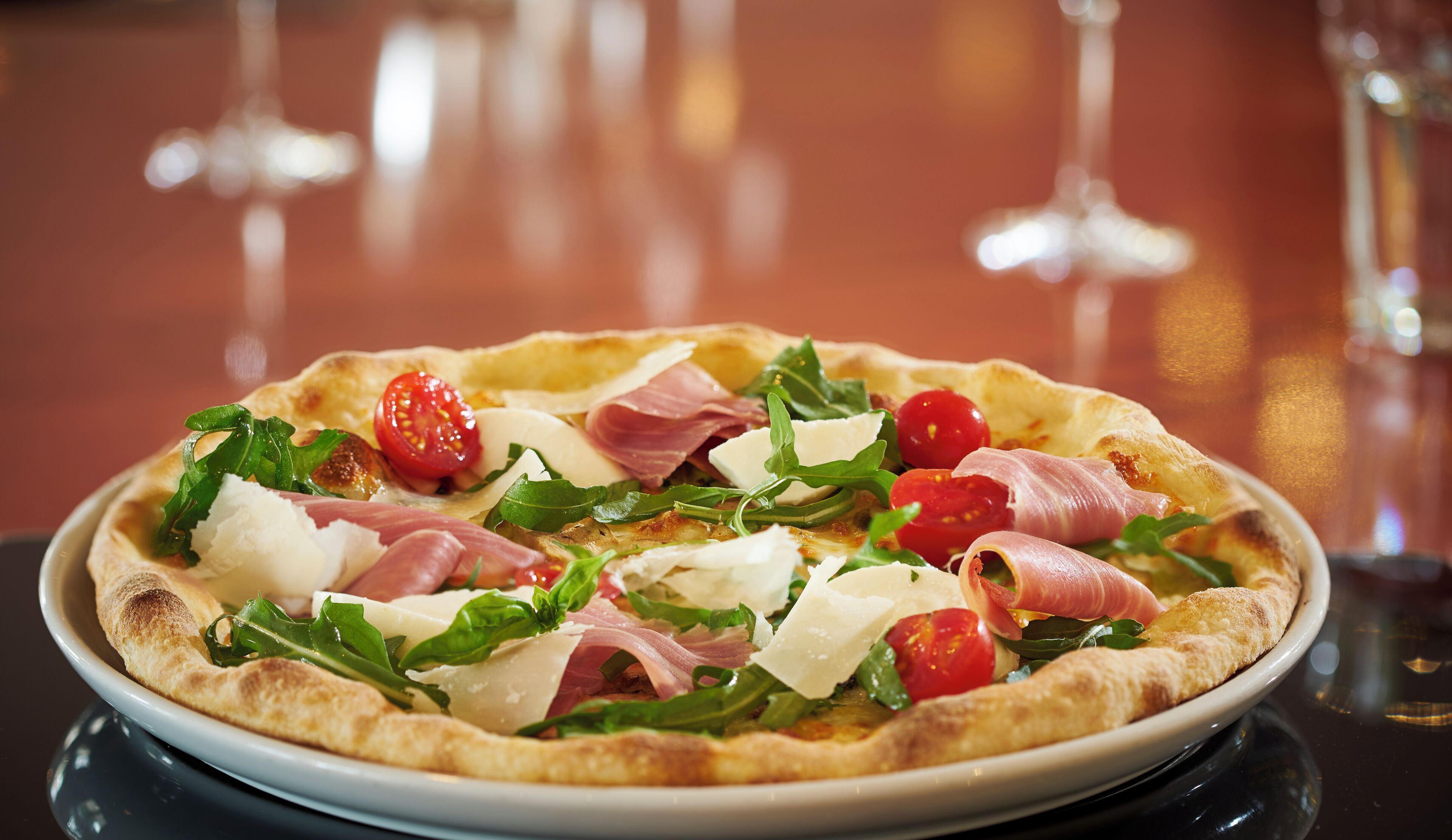 Une pizza garnie de divers ingrédients, servie sur une assiette blanche.