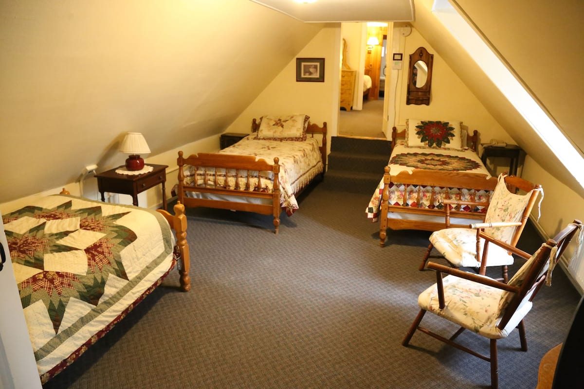A bedroom with two beds, a chair, and a nightstand.