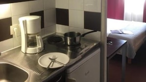 A compact kitchenette with a microwave, coffee maker, and a small stove. - Appartéa Grenoble Alpexpo (Grenoble)