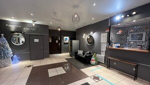 A modern lobby with a reception desk, a Christmas tree, and a wall-mounted mirror. - Appartéa Grenoble Alpexpo (Grenoble)
