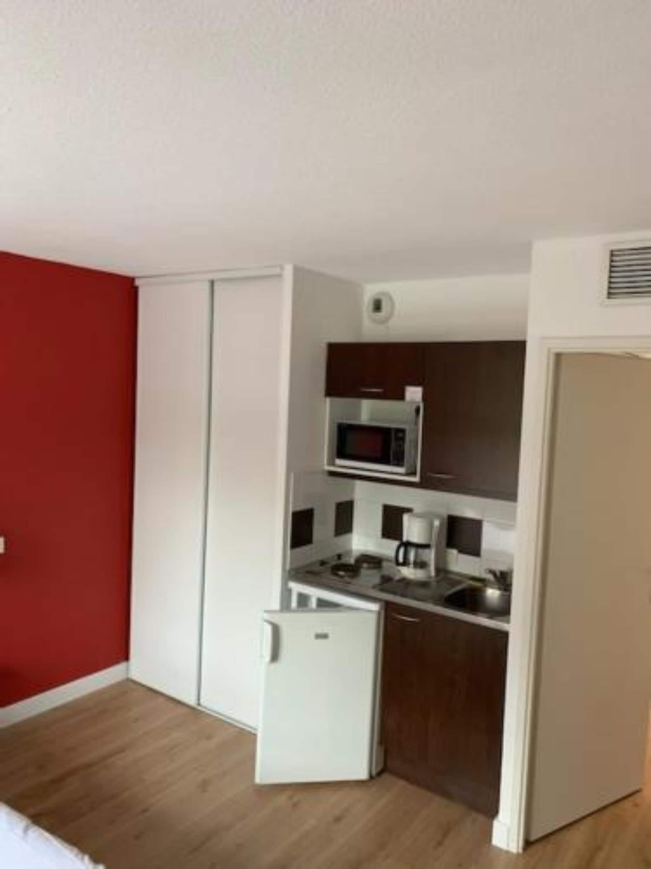 A compact kitchen with a microwave, coffee maker, and a small refrigerator.