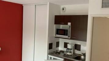 A compact kitchen with a microwave, coffee maker, and a small refrigerator.