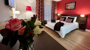 A hotel room with a bed, a desk, a TV, and a vase of flowers. - Appartéa Grenoble Alpexpo (Grenoble)