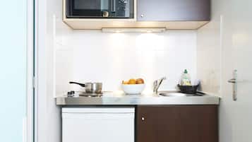 A compact kitchen with a microwave, sink, and a small refrigerator.