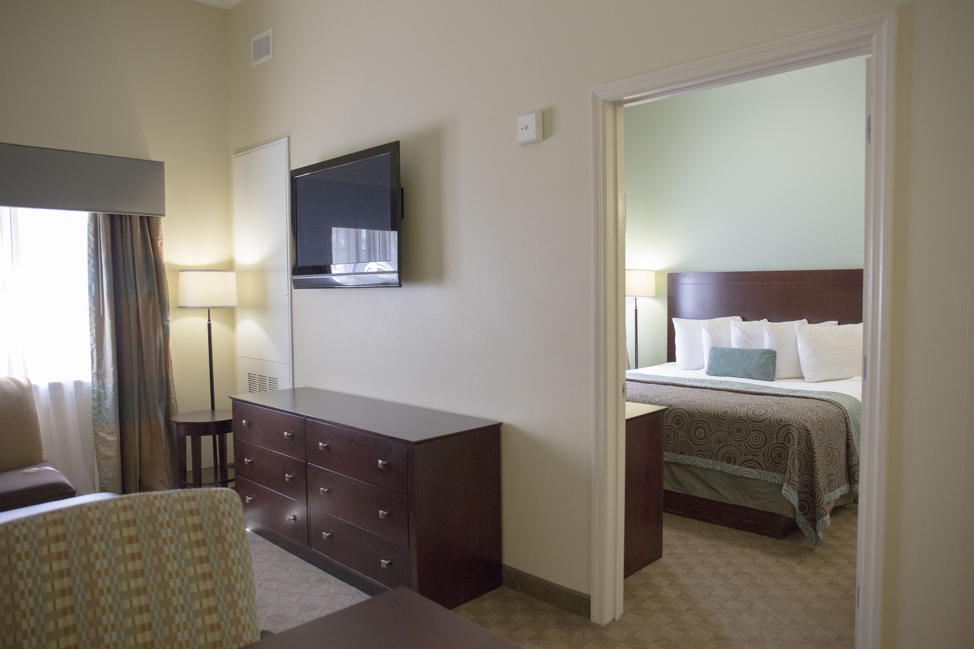 Una habitación de hotel con una cama, un aparador, un televisor y un escritorio.