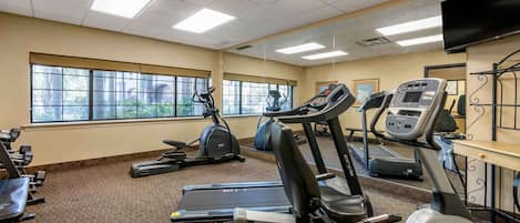 Un gimnasio con cintas de correr, elípticas y máquinas de pesas.