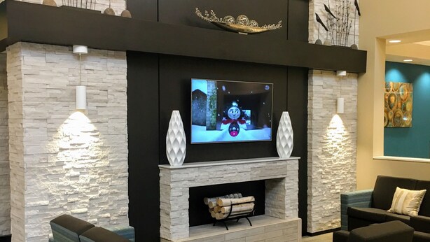 A modern living room with a stone fireplace, a flat-screen TV, and comfortable seating.