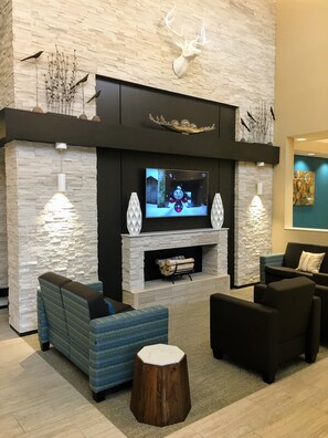 Una sala moderna con chimenea de piedra, televisor de pantalla plana y asientos cómodos.