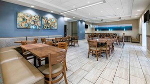 A spacious restaurant with multiple dining tables and booths, a modern ceiling design, and abstract wall art.