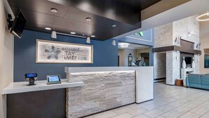 A reception area with a stone-textured counter, a mounted television, and a framed sign that reads "extended stay AMERICA".