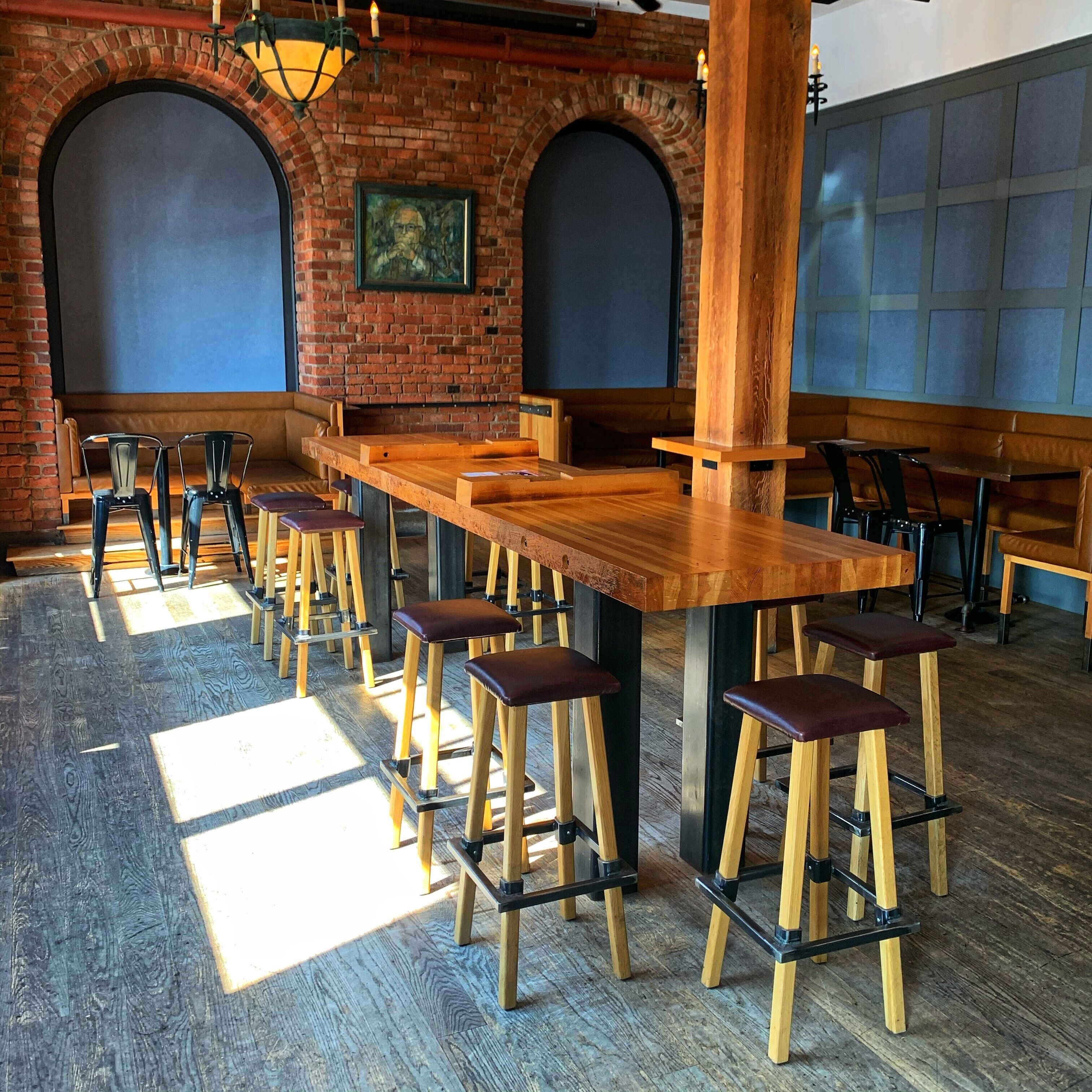 A restaurant interior with brick walls, wooden tables, and bar stools.