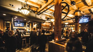 A crowded bar with wooden beams and a menu board. - Swans Brewery, Pub and Hotel (Victoria)