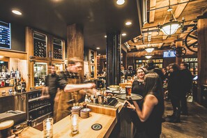 A bar with wooden interiors, a bartender, and patrons.