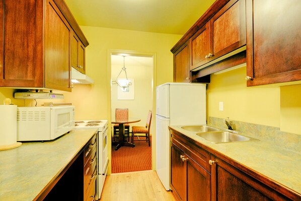 A compact kitchen with wooden cabinets, a microwave, a stove, and a refrigerator.