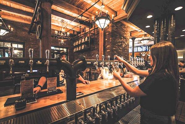 A bar with a wooden counter, multiple taps, and a menu board.