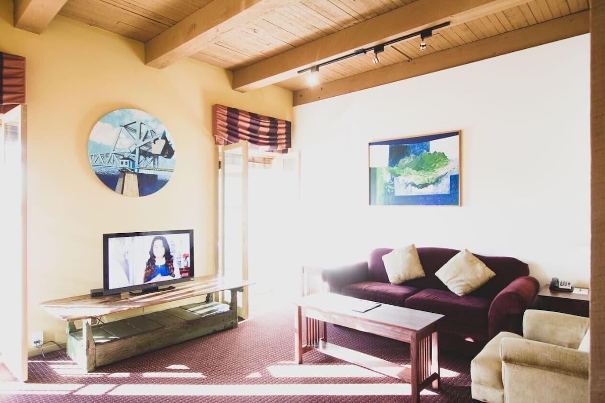 A living room with a television, a couch, and a coffee table. There are two paintings on the wall.