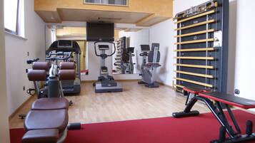 Un gimnasio con equipo de ejercicio, un televisor y un estante de pared.