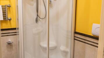 A corner shower enclosure with a glass door, a toilet, and a towel rack.