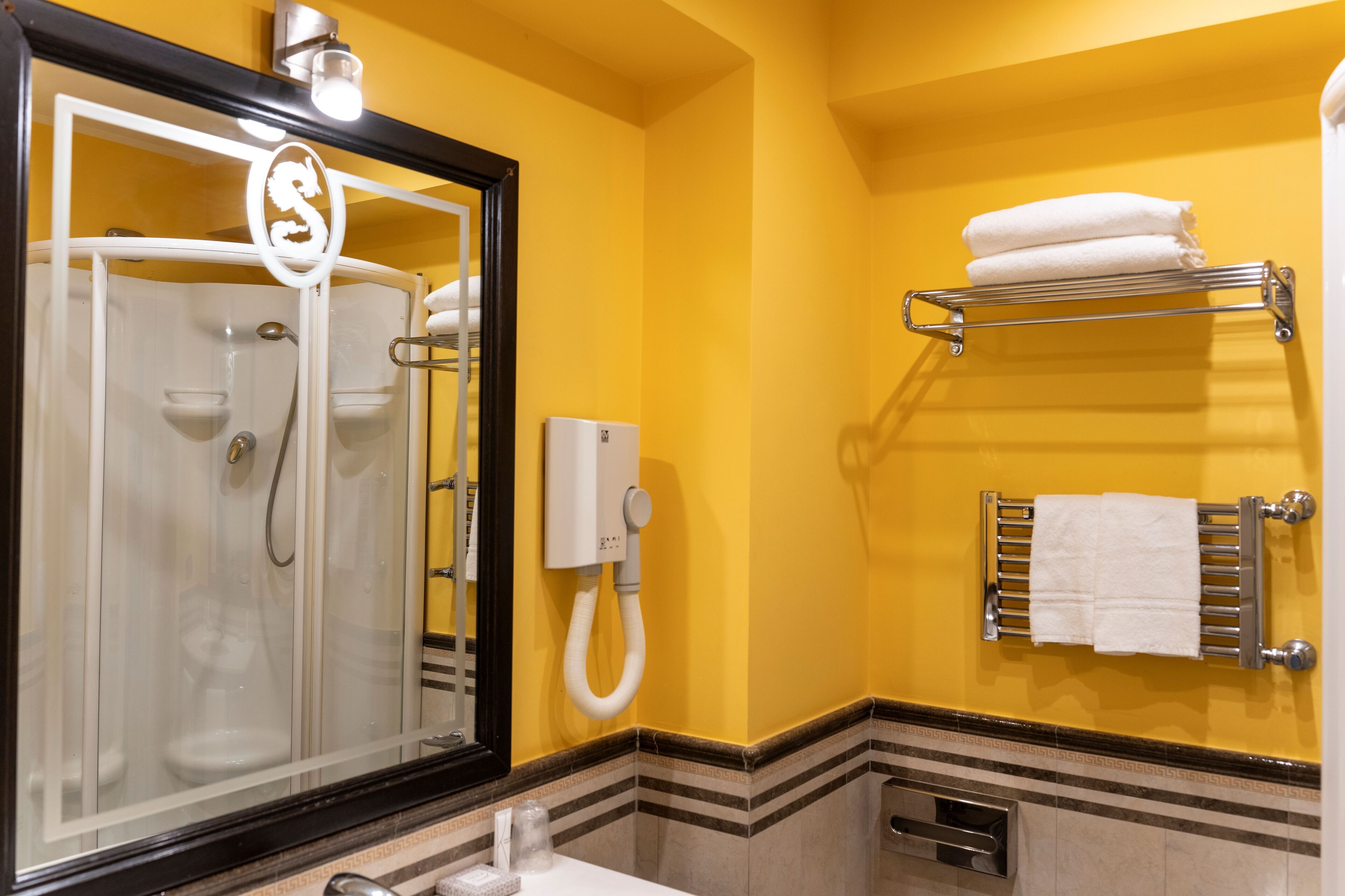 Une salle de bain avec une douche à parois de verre, un porte-serviettes avec des serviettes pliées et un téléphone blanc.