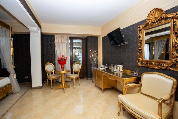A luxurious room with a large mirror, a gold-toned desk, and elegant chairs.