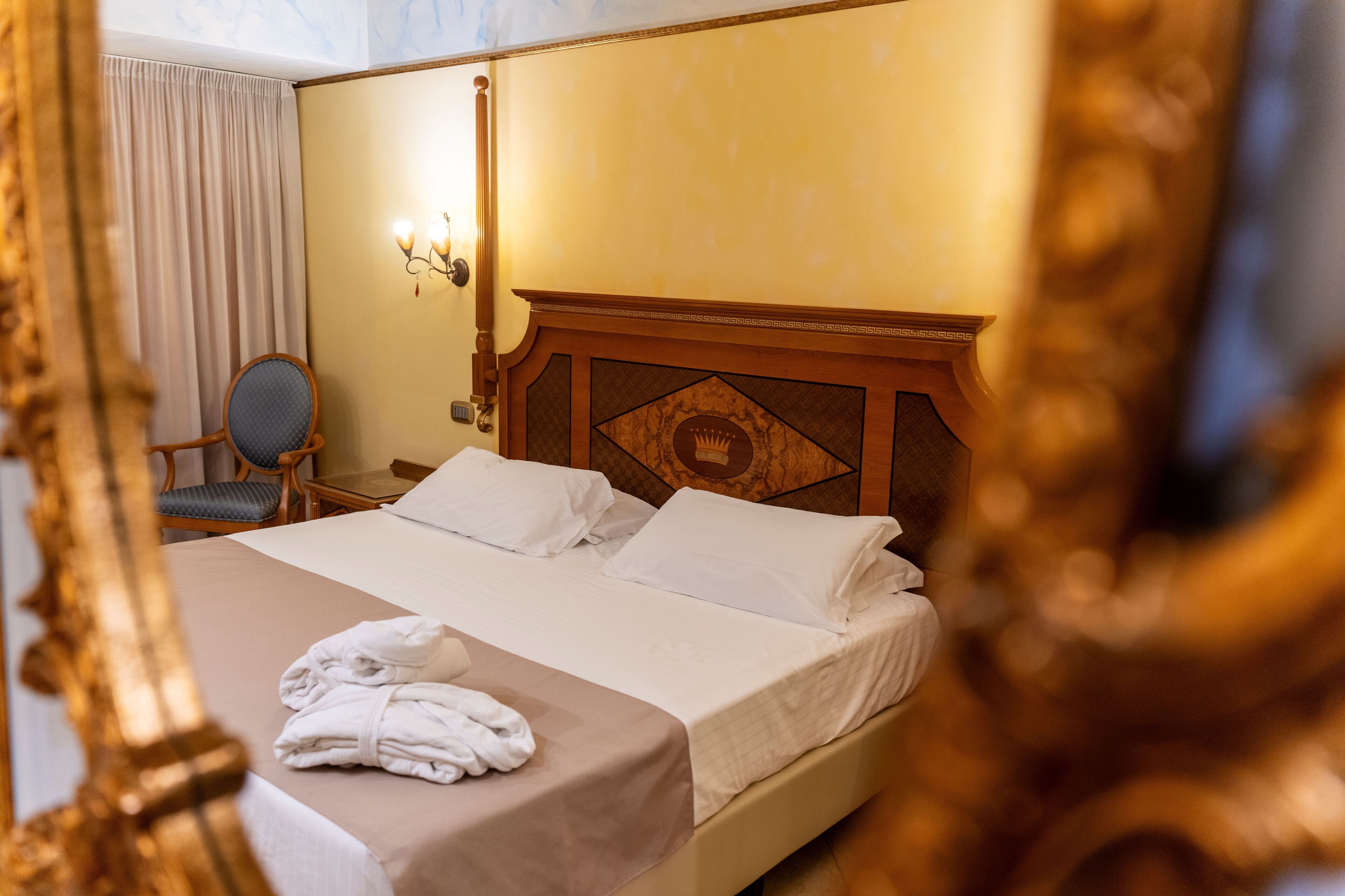 Ein Hotelzimmer mit einem großen Bett, einem Sessel, einem Schreibtisch und einer Wandlampe.