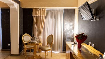Une chambre d’hôtel dotée d’un coin repas comprenant deux chaises, une table et un vase de fleurs.