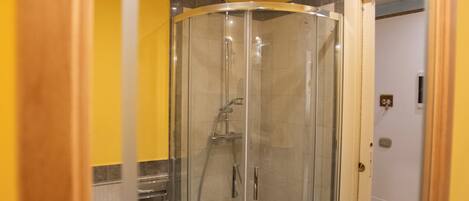 A bathroom with a glass-enclosed shower, a sink, and a mirror with a wooden frame.