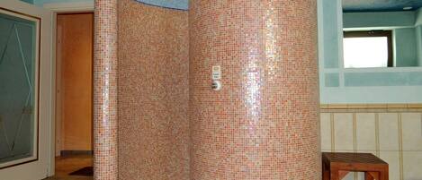 A room with a tiled column, a wooden bench, and a door leading to another room.