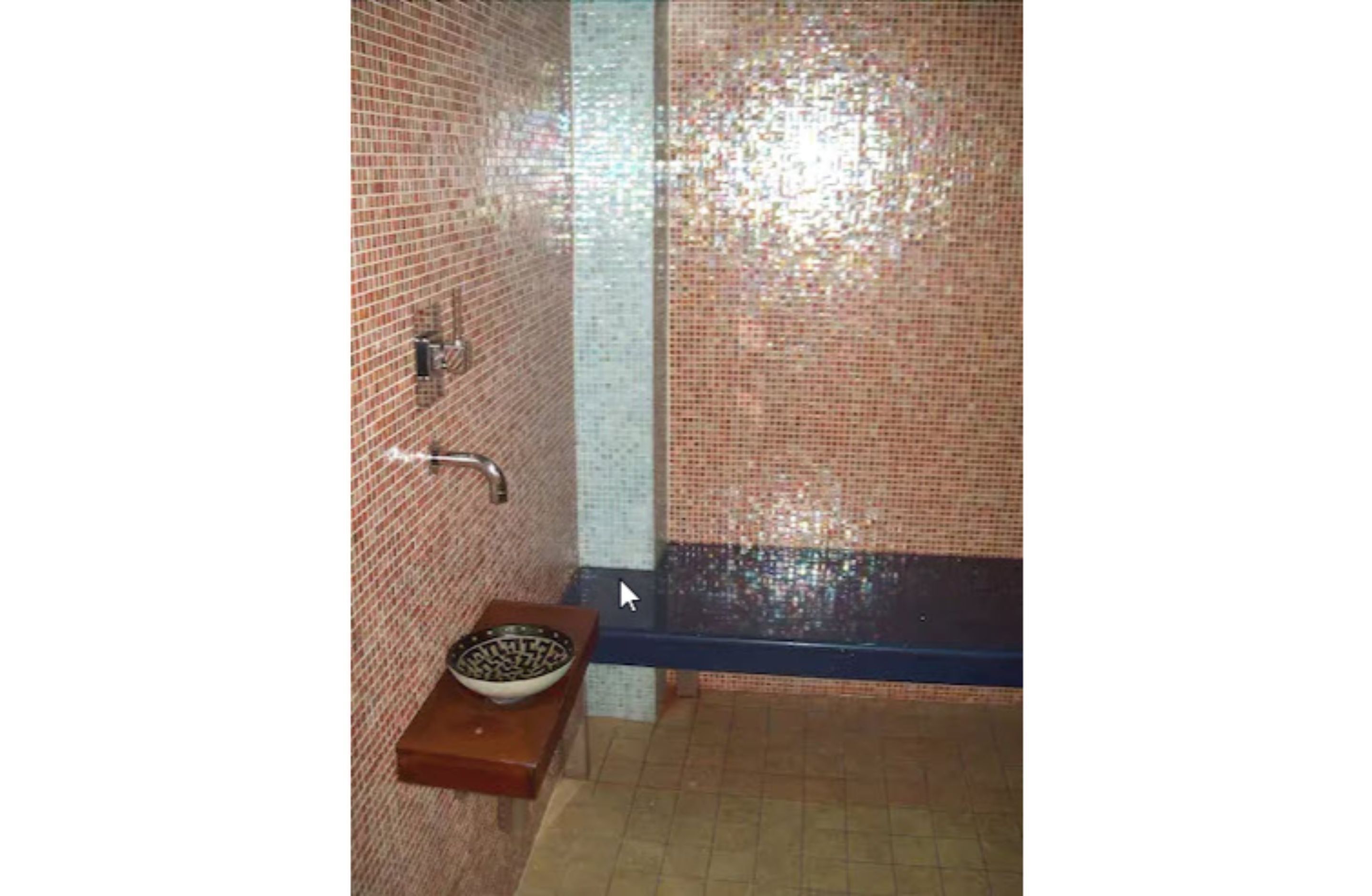 Une salle de bain avec un mur carrelé, un lavabo avec un receveur et un espace douche.