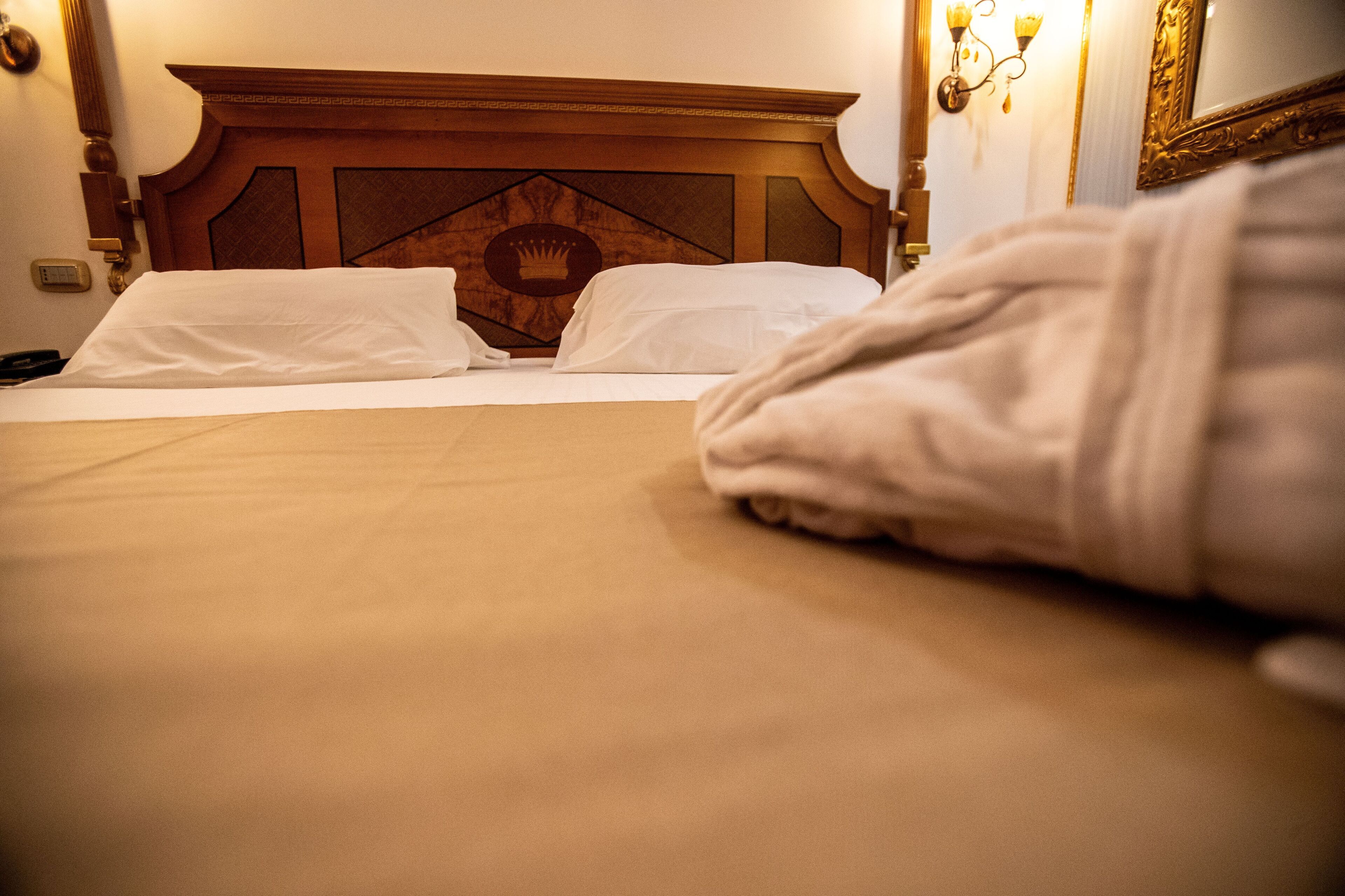 A hotel room with a wooden headboard, two white pillows, and a neatly made bed.