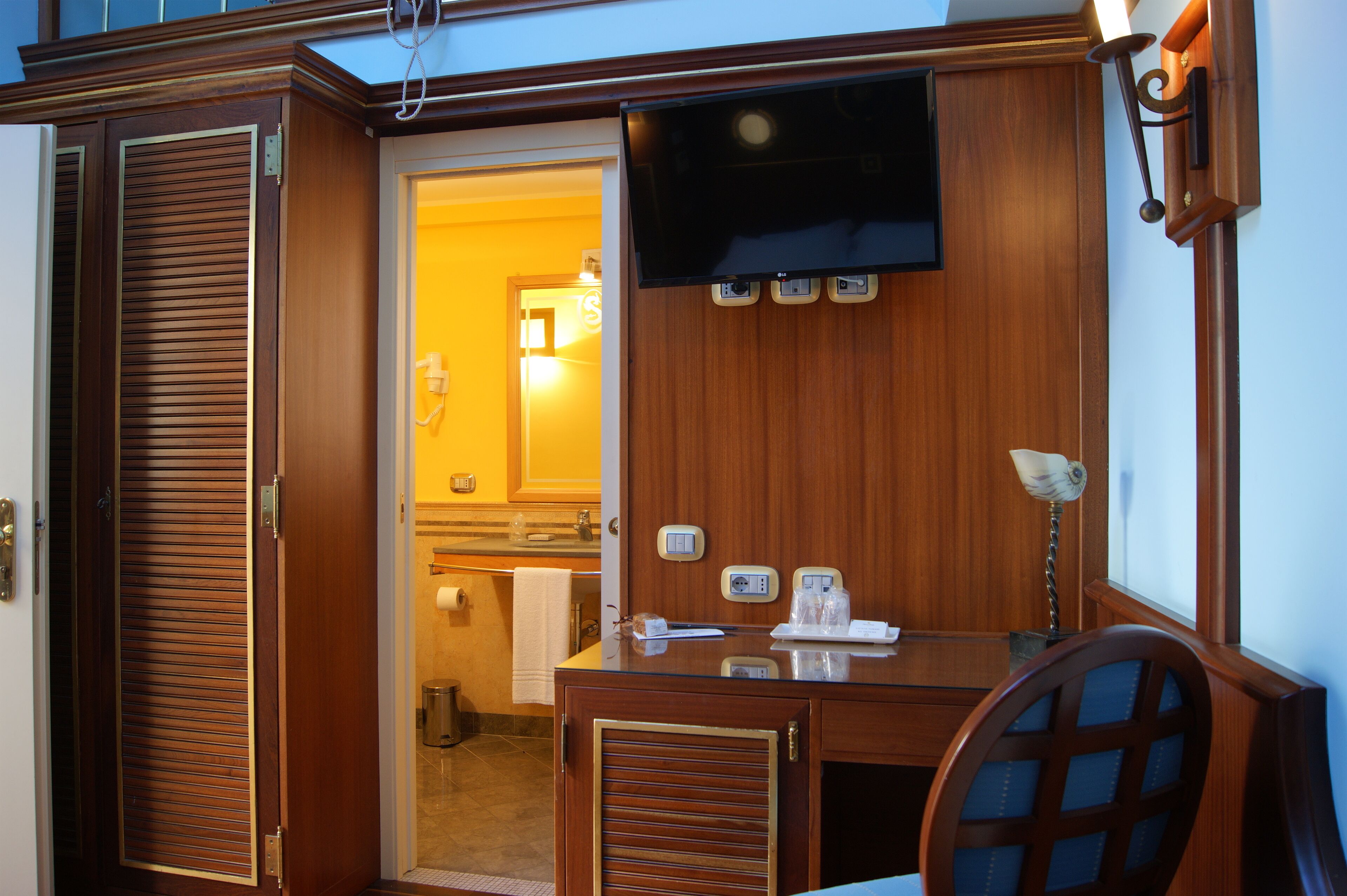 A wooden interior with a TV mounted on the wall, a desk, and a chair.
